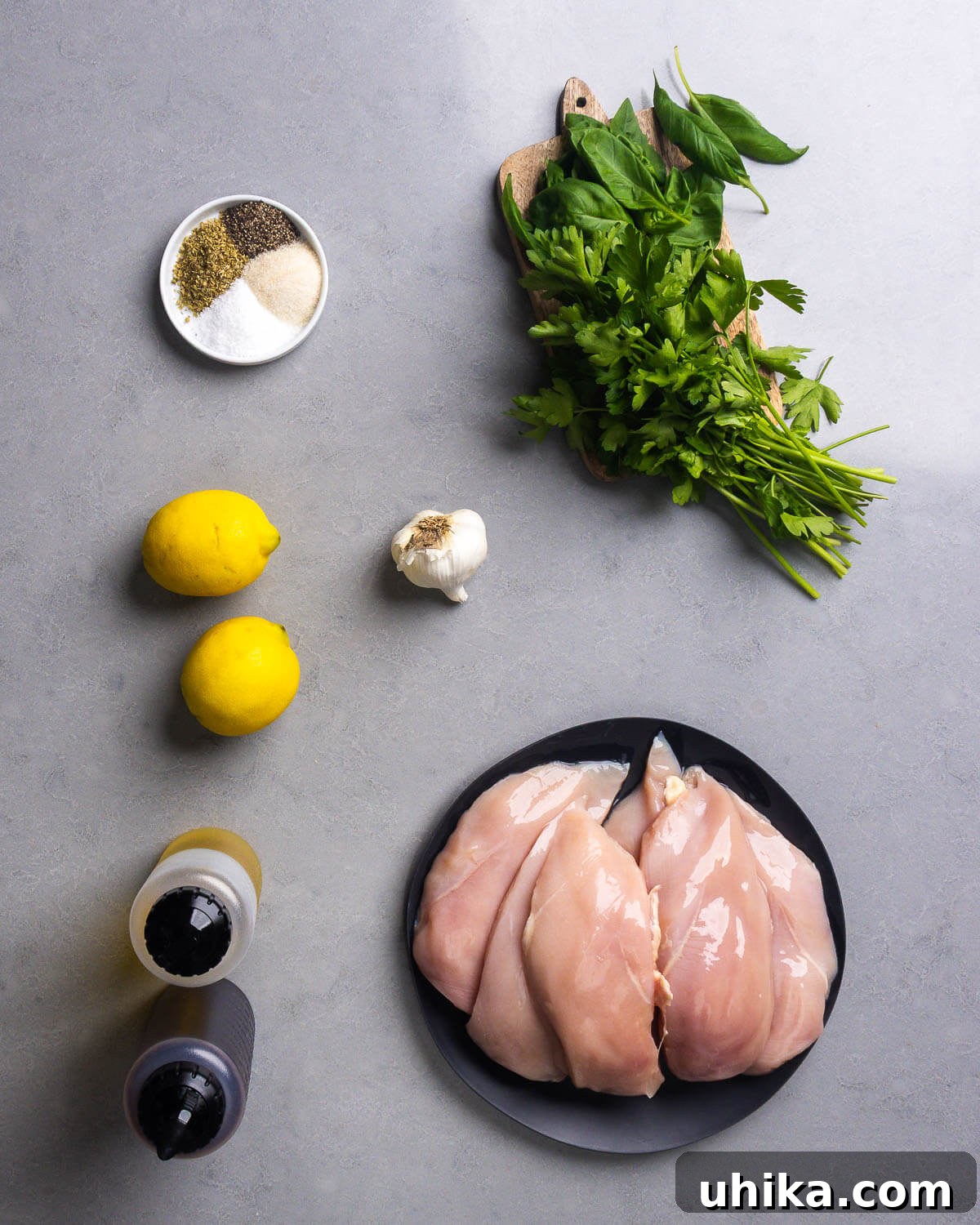 Chicken Spiedies Recipe: Tangy Italian-Marinated Grilled Sandwich 4 Ingredients shown: spices, basil, parsley, lemons, garlic, olive oil, red wine vinegar, and chicken breasts.