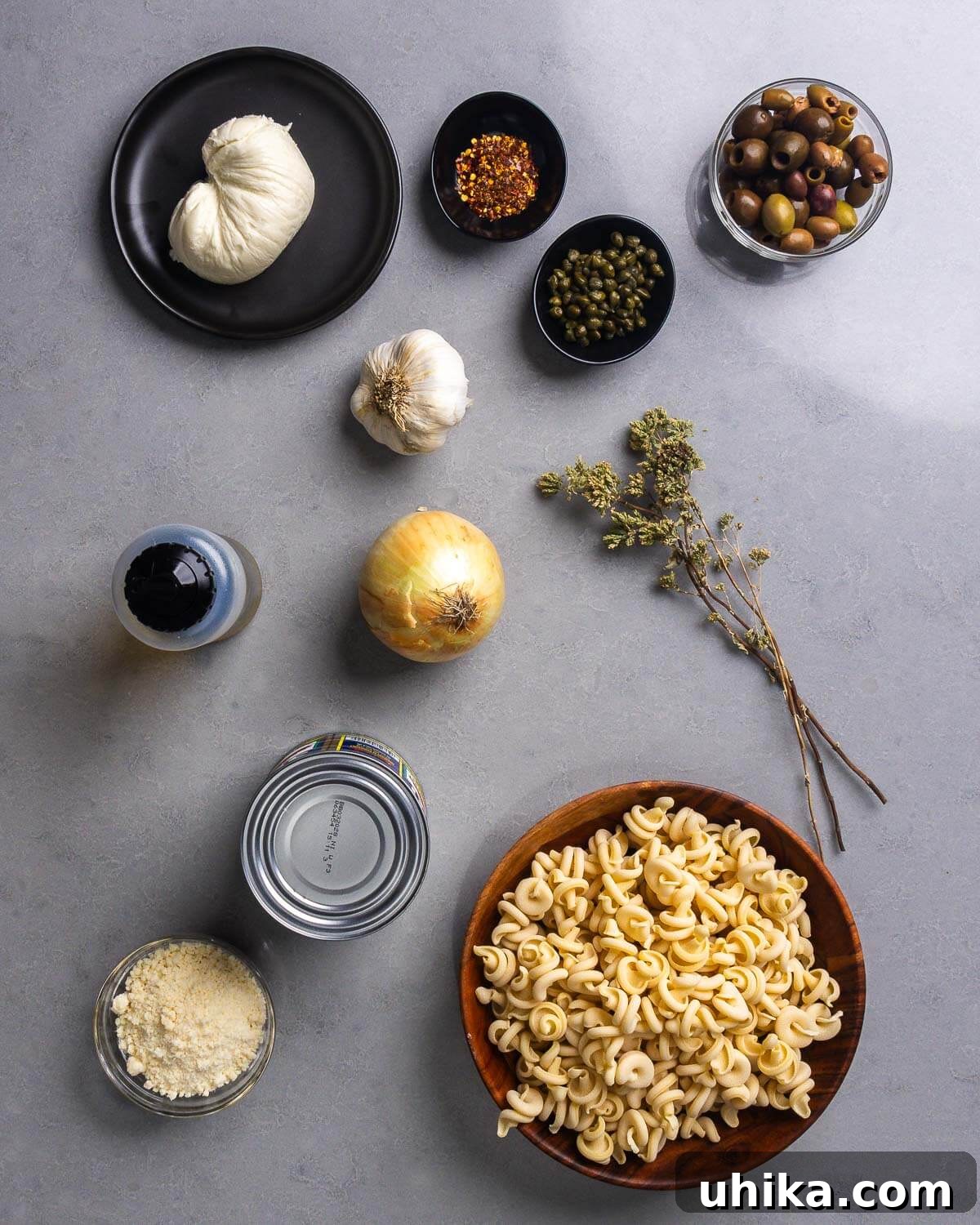 Pasta alla Vesuviana: Fiery Neapolitan Pasta 4 Ingredients shown: fresh mozzarella, hot red pepper flakes, capers, olives, garlic, olive oil, onion, Sicilian oregano, Parmigiano Reggiano, canned tomatoes, and pasta.