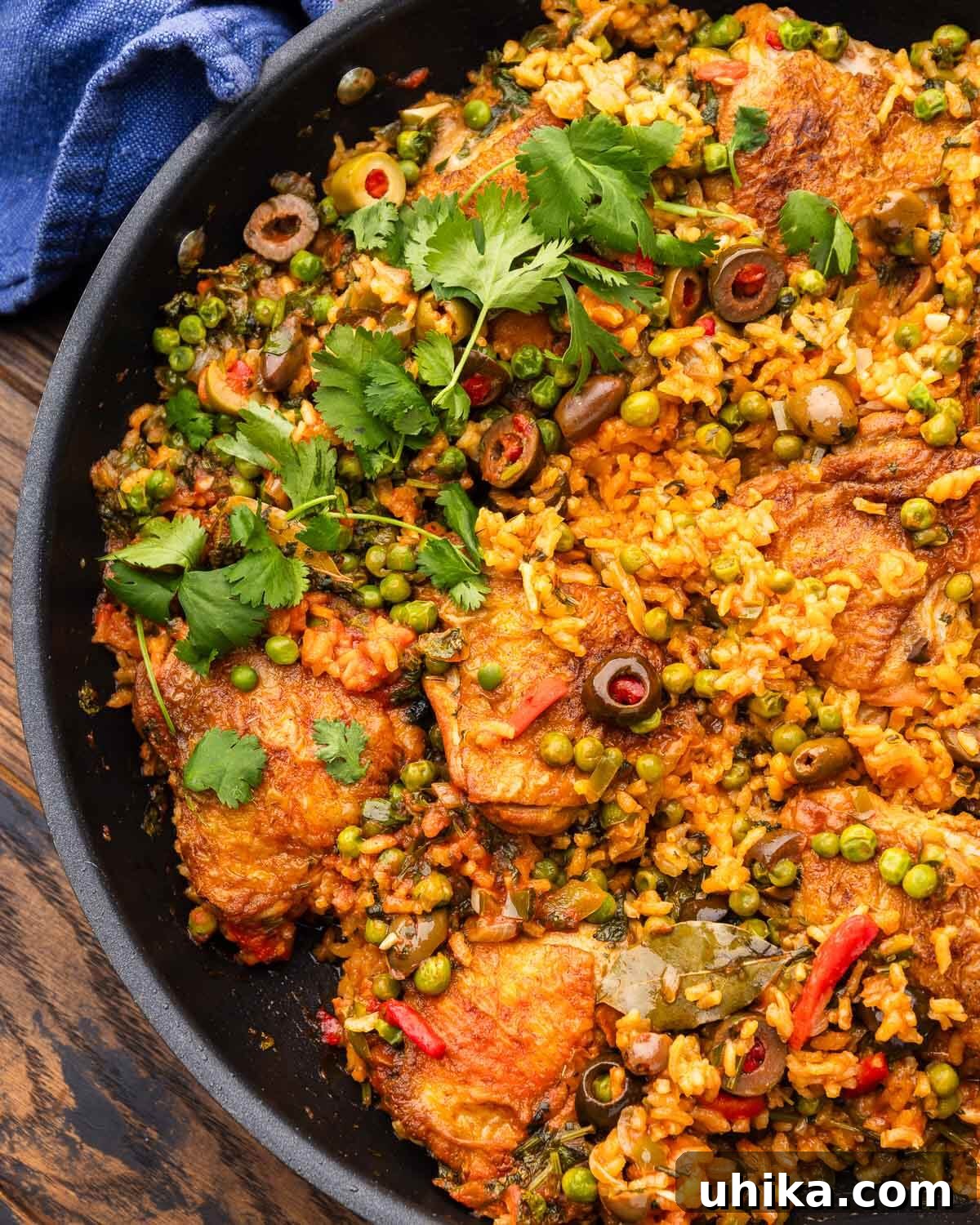 Arroz con Pollo: Spanish-Style Chicken and Rice 2 Black pan with arroz con pollo topped with cilantro garnish.
