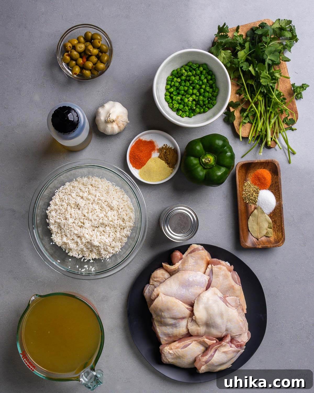 Arroz con Pollo: Spanish-Style Chicken and Rice 4 Ingredients shown: olives, peas, cilantro, olive oil, garlic, spices, bell pepper, rice, tomato sauce, chicken stock, and chicken thighs.