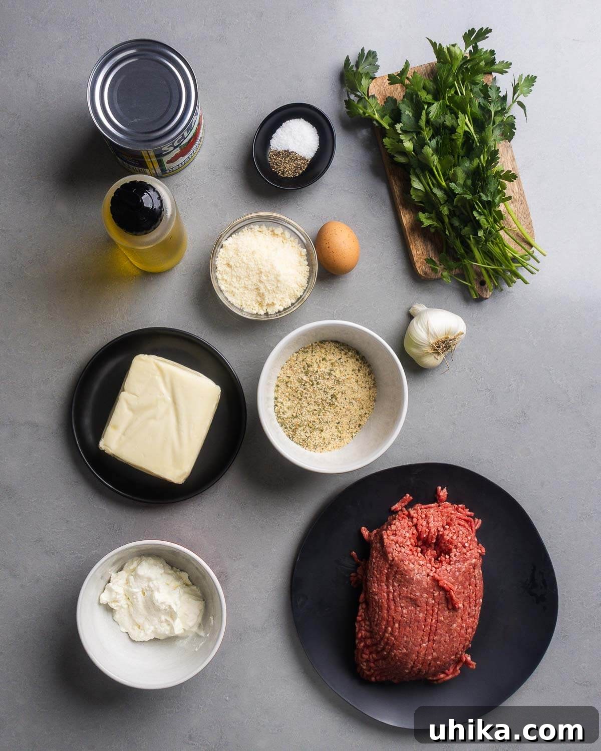Mini Italian-Style Stuffed Meatloaves 4 Ingredients shown: canned tomatoes, olive oil, salt, pepper, parmesan, egg, parsley, garlic, mozzarella, breadcrumbs, ricotta, and ground sirloin.