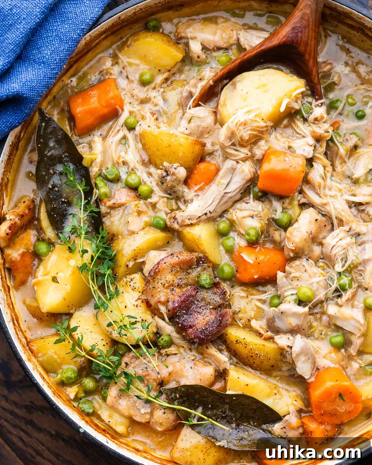 Hearty Chicken and Potato Stew for Cozy Weeknight Dinners 2 Wooden spoon scooping out chicken potato pea stew.