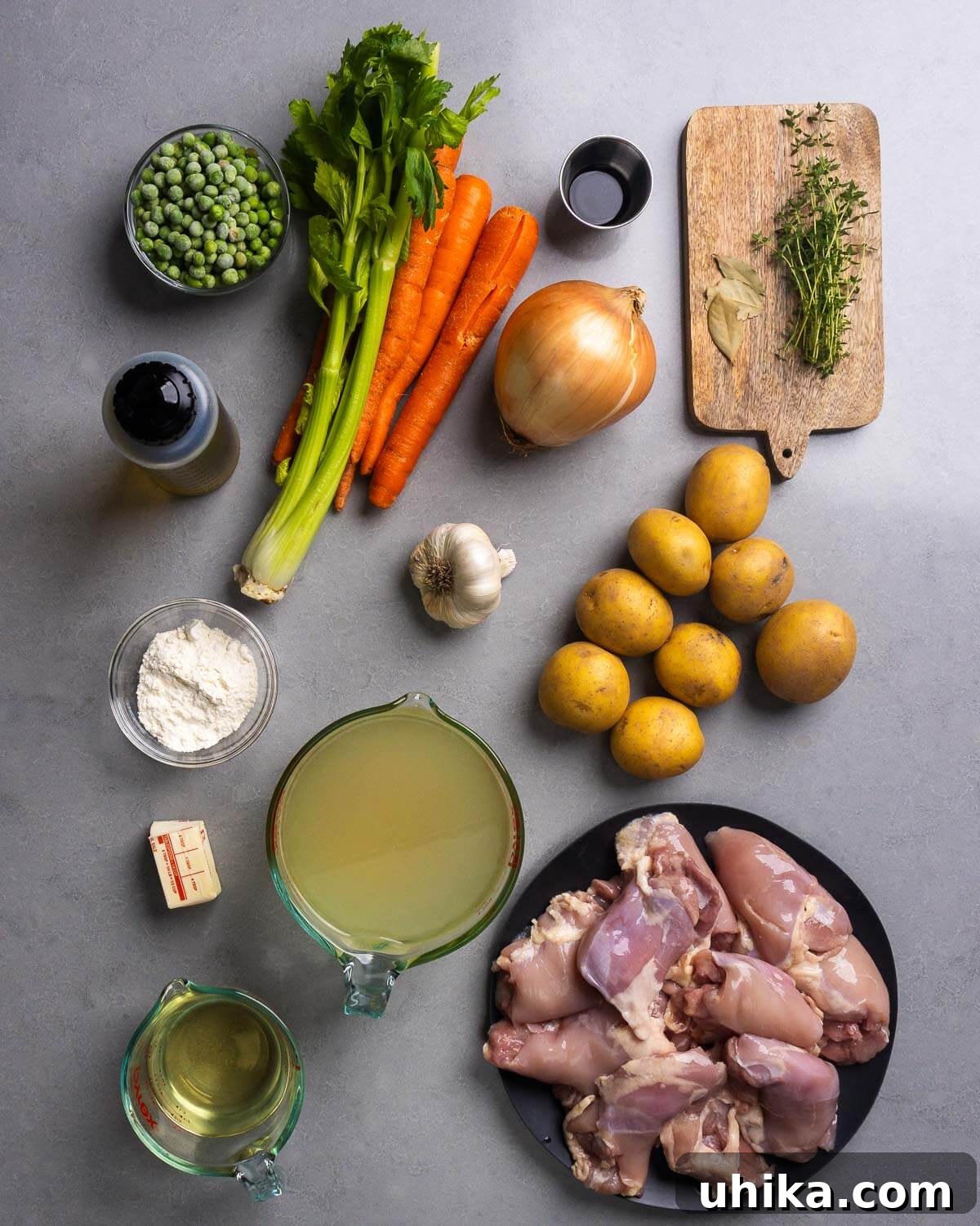 Hearty Chicken and Potato Stew for Cozy Weeknight Dinners 4 Ingredients shown: olive oil, peas, celery, carrots, worcestershire sauce, onion, bay leaves, thyme, flour, garlic, potatoes, butter, chicken stock, wine, and chicken thighs.