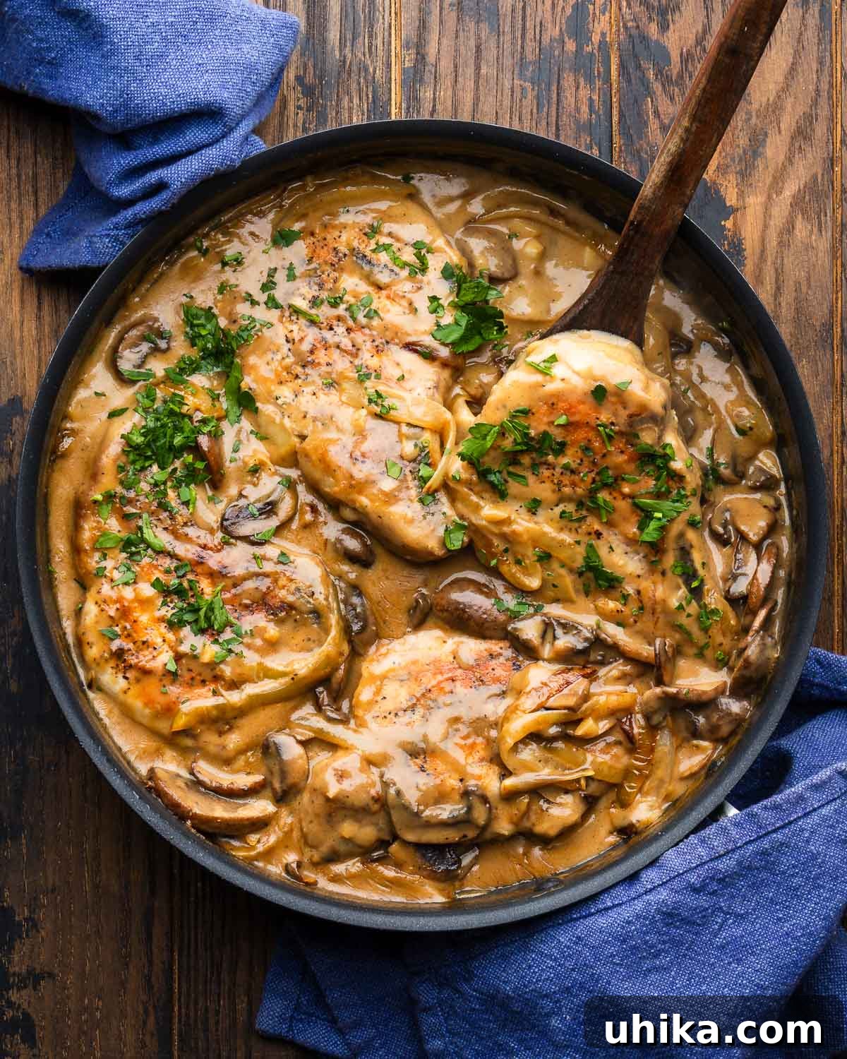 Smothered Pork Chops in Creamy Mushroom Sauce 2 Smothered pork chops in large black pan.