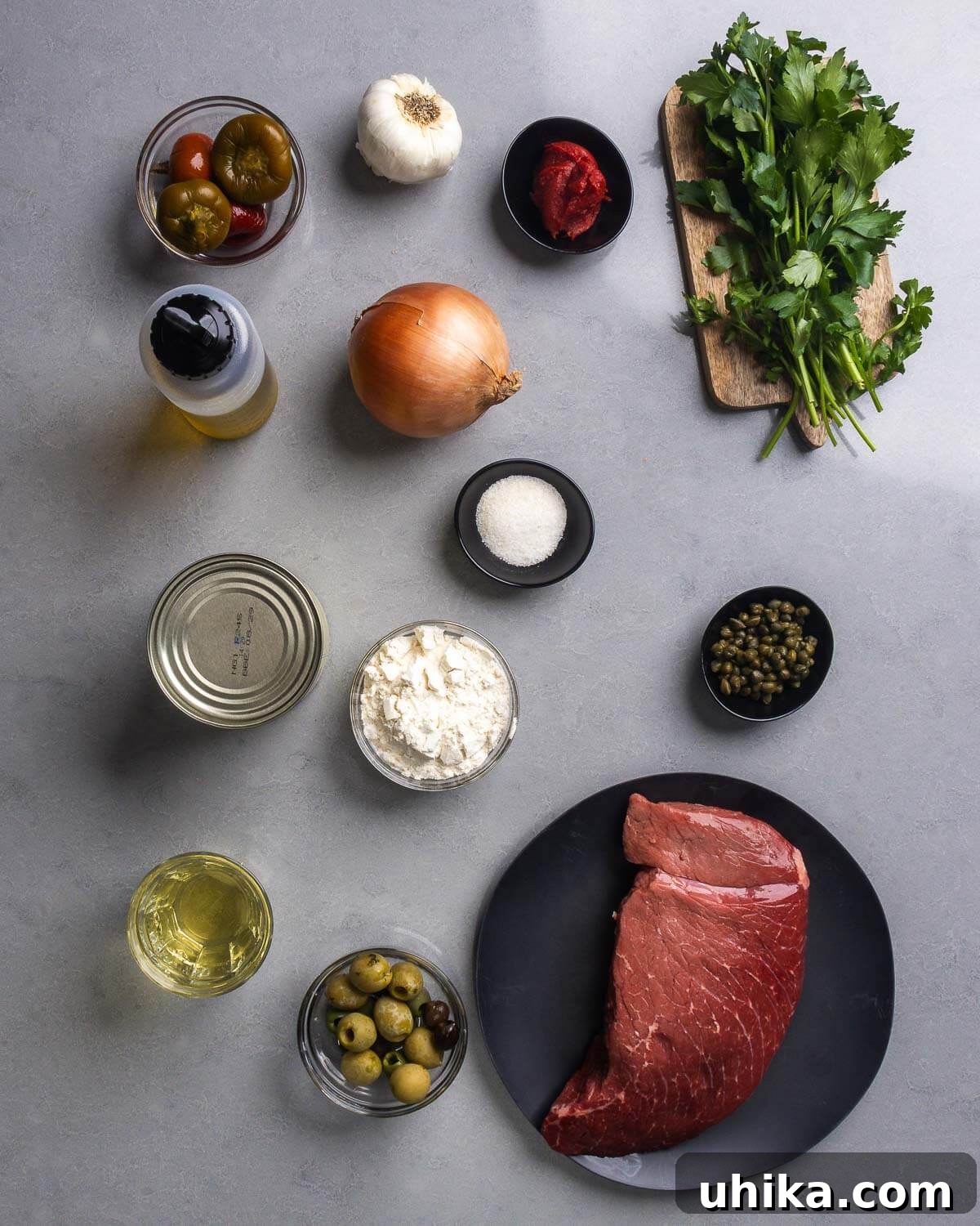 Mediterranean Braised Steak with Capers, Olives and Peppers 4 Ingredients shown: cherry peppers, olvive oil, garlic, onion, tomato paste, parsley, canned tomatoes, flour, sugar, capers, white wine, olives, and beef top round.